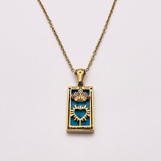 Front view of an enchanting gold plated necklace perfected with a rectangular tarot card, the Empress (-III-), sculpted with stunning gold plated artistry, detailed with pink and white zircons, and blue lapis lazuli replica stone backed.