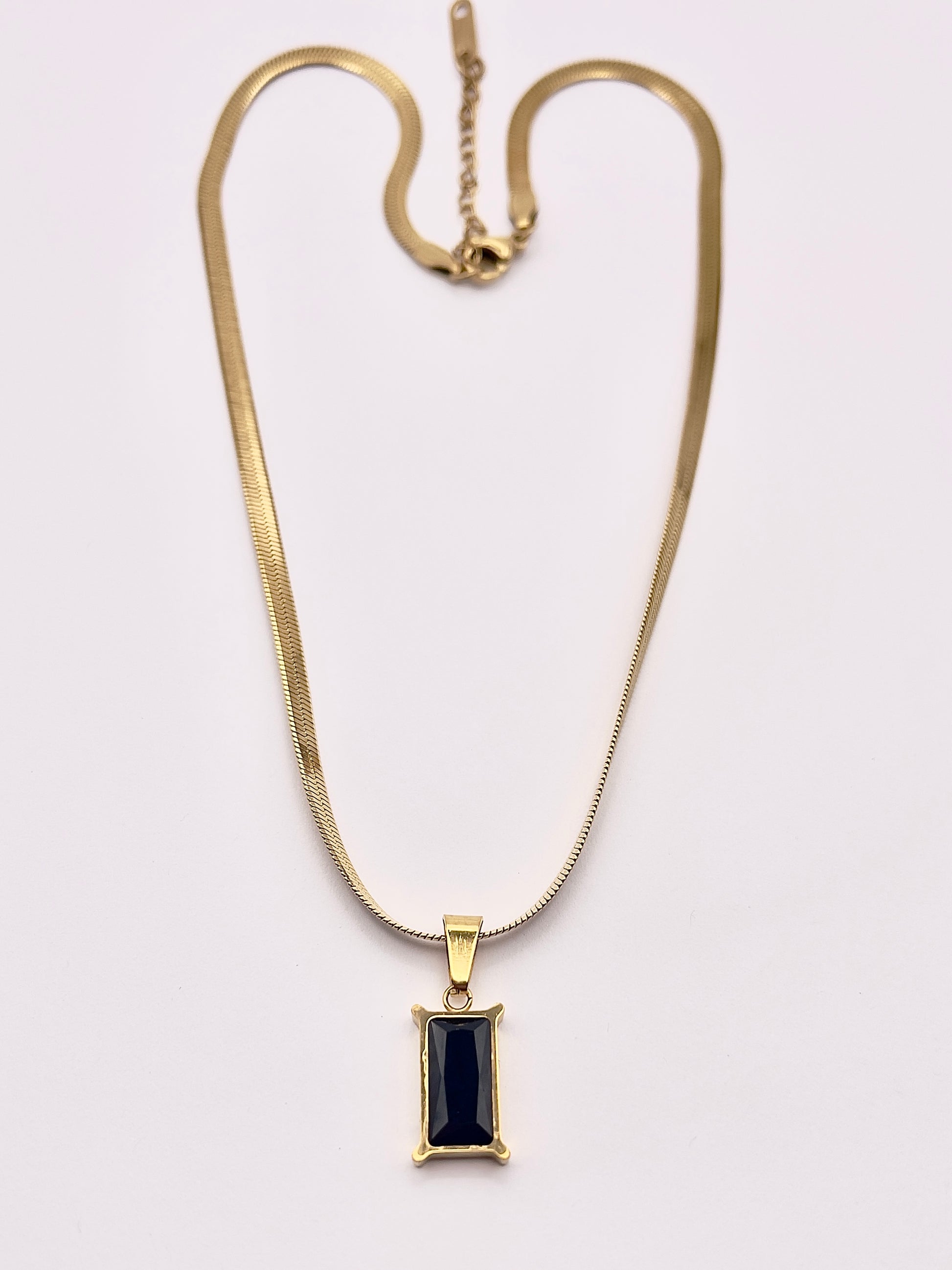 Full view of Fthi, A distinguished flowing gold plated herringbone necklace complimented with an obsidian black zircon.