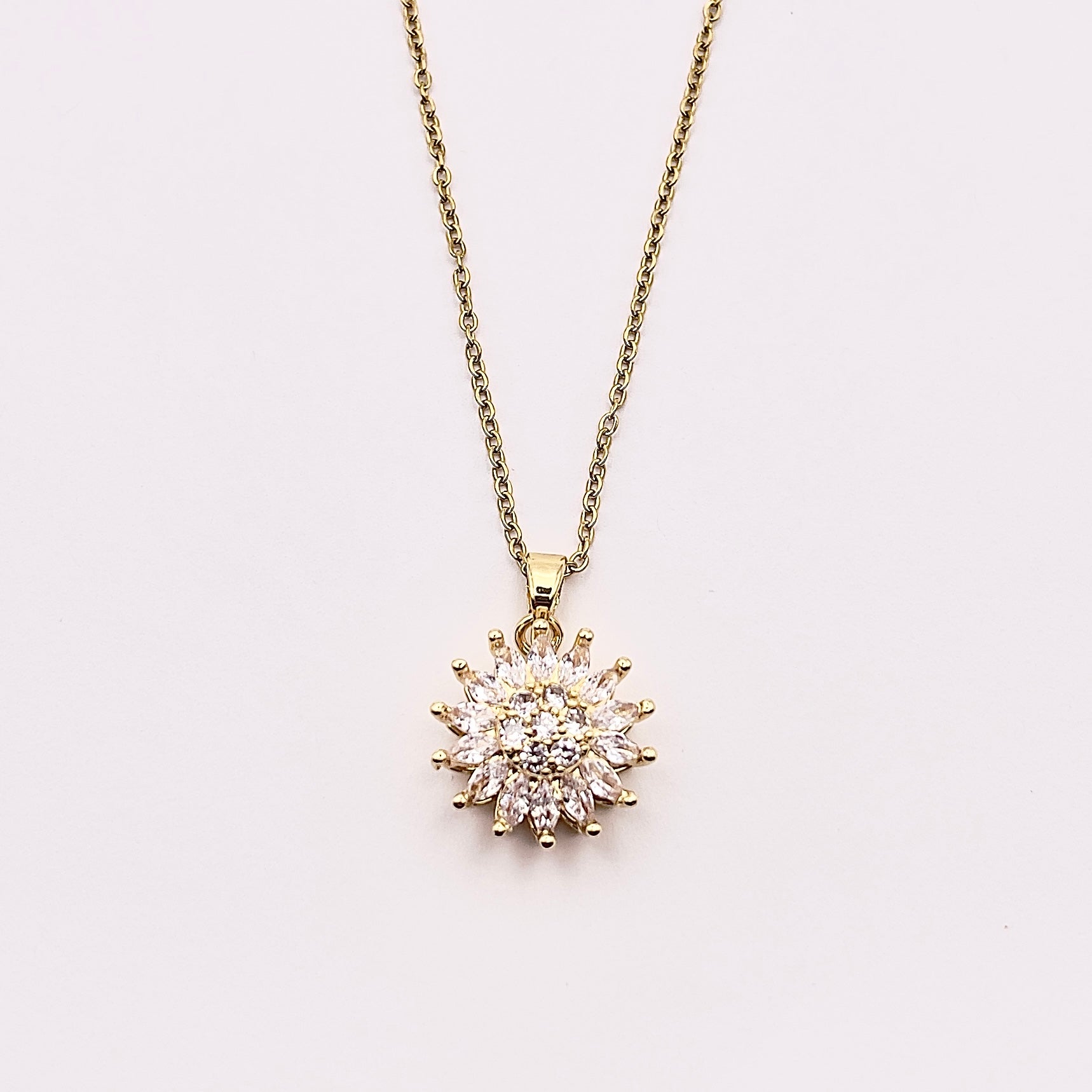 Close up front view of Ilio, a stunning gold plated rotating sunflower zircon necklace.