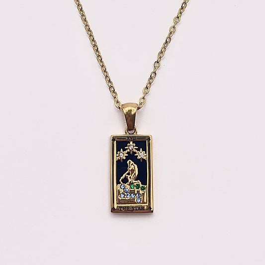 Front view of an enchanting gold plated necklace perfected with a rectangular tarot card, the Star (-XVII-), sculpted with stunning gold plated artistry, detailed with white and green zircons, and black stone backed.