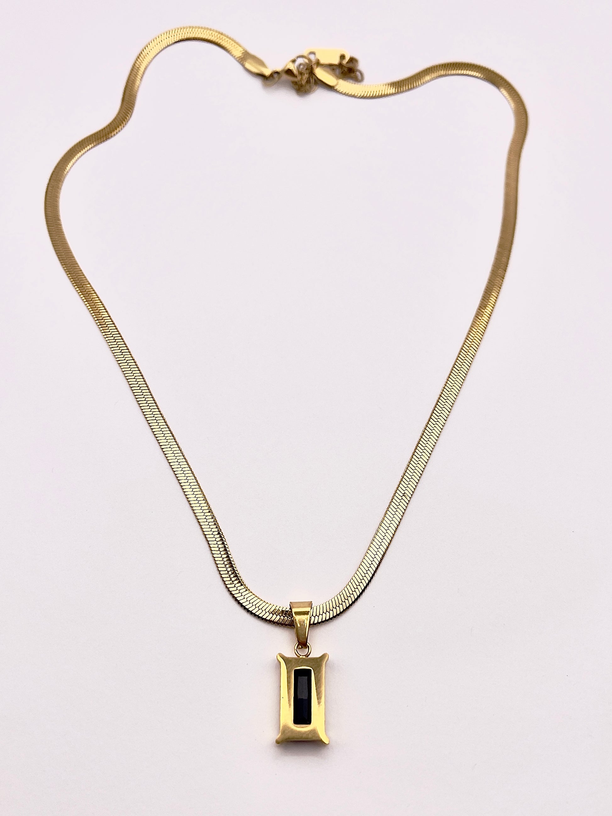 Back view of Fthi, A distinguished flowing gold plated herringbone necklace complimented with an obsidian black zircon.