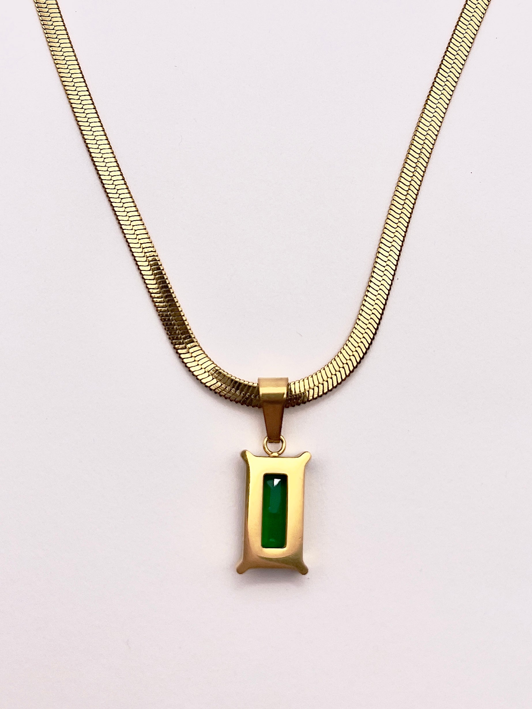 Back view of Fthi, A distinguished flowing gold plated herringbone necklace complimented with an emerald green zircon.