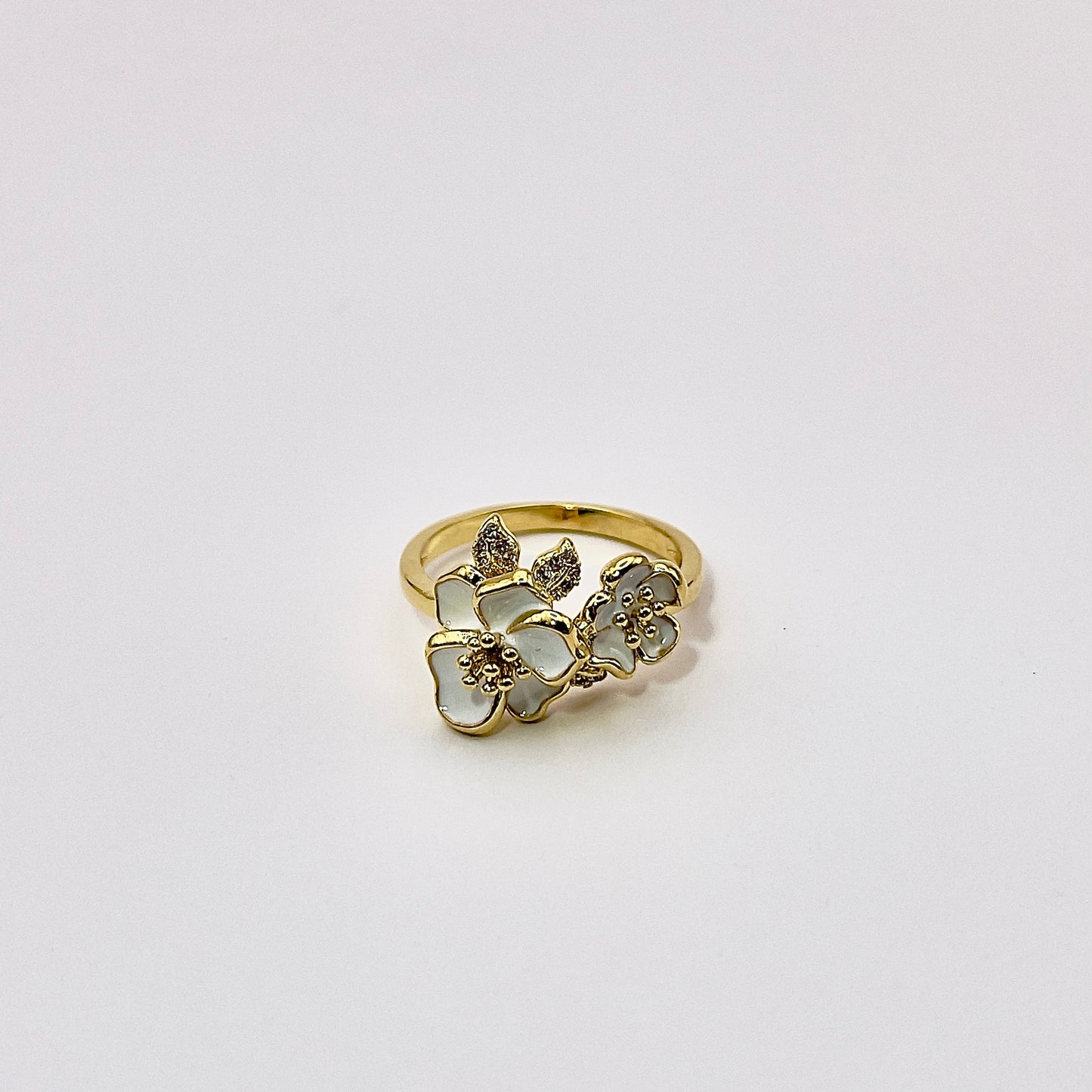 Front view photo of Etal, an alluring gold plated ring with intricately sculpted white petaled enamel flowers complimented with inlayed zircon petals.